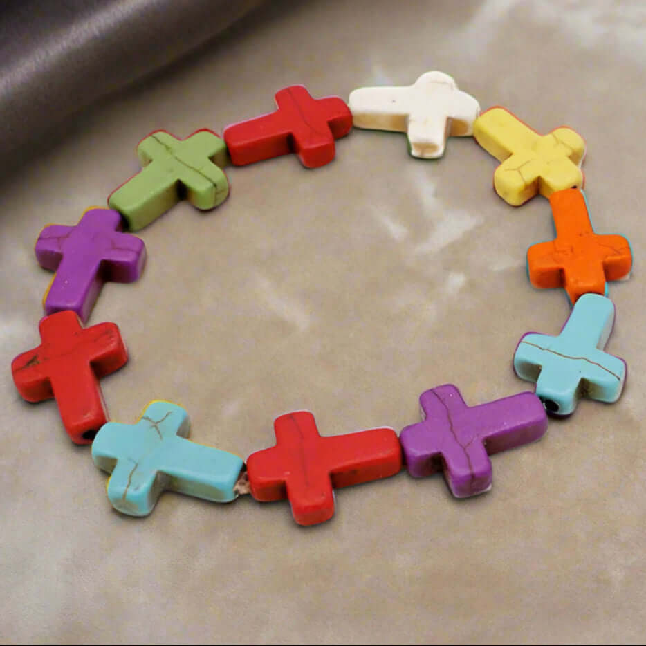 Colorful cross bracelet featuring vibrant wooden beads in various shades arranged on a soft surface.