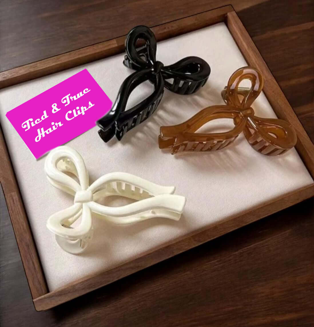 Collection of Tied and True hair clips in black, brown, and cream bow shapes on a display.