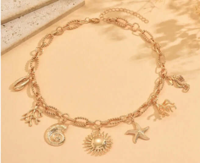 WALKIN ON SUNSHINE CHARM NECKLACE featuring gold-tone charms including sun, starfish, seashells, and seahorse on a paperclip chain.