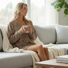 Model wearing FIERCE COMFORT SKORT SET in light French beige leopard print, relaxing on a couch.