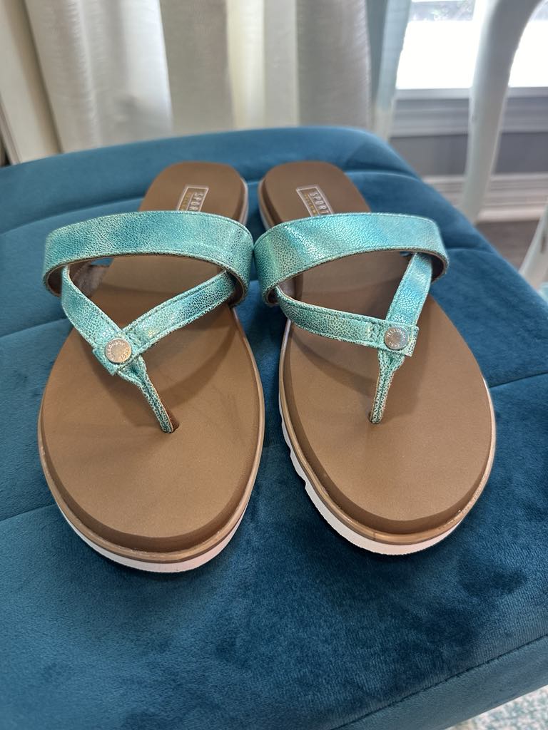 YELLOW BOX - SHAYNE turquoise shimmer flip flops with silver accents on a teal background.