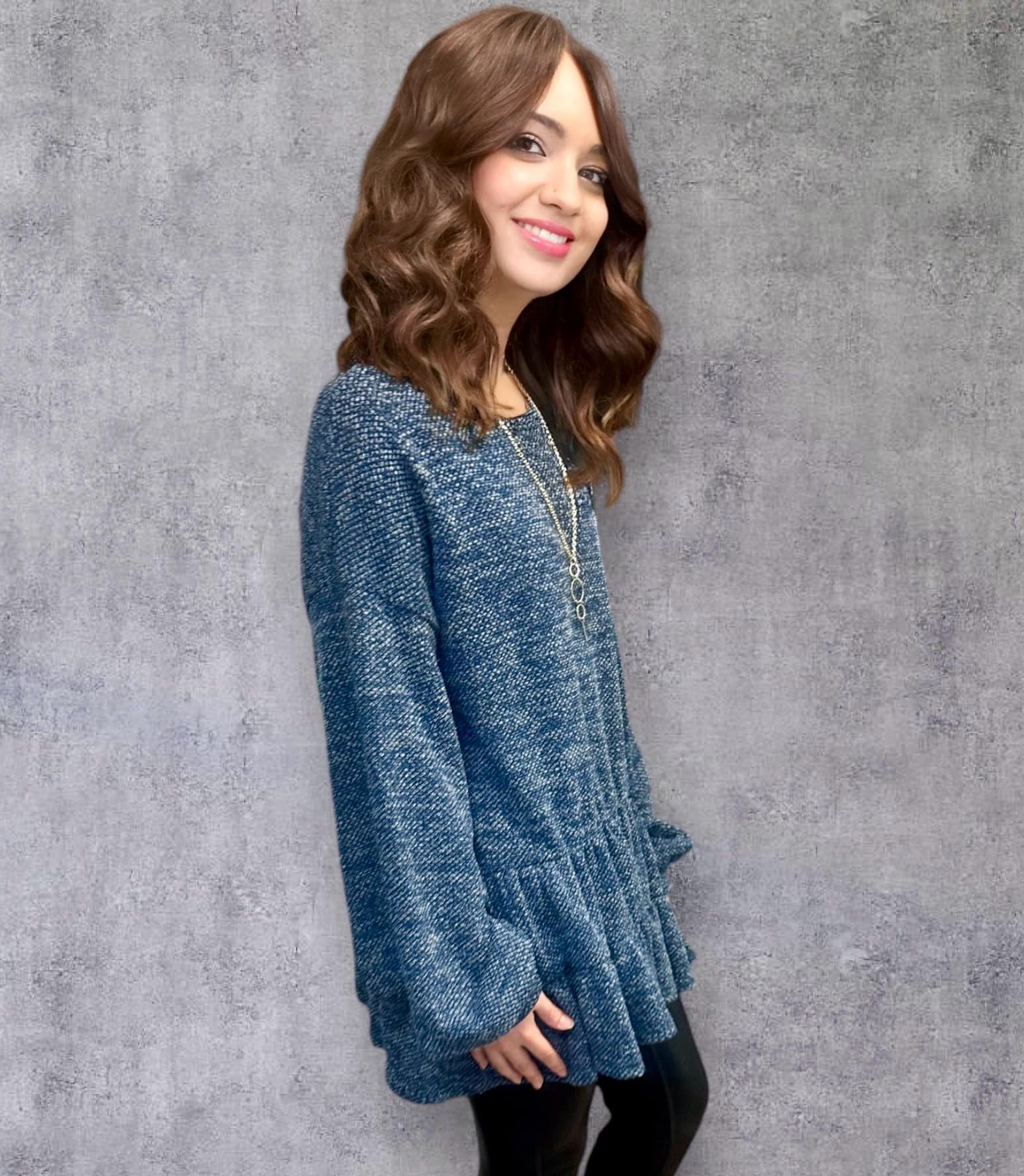 Model wearing blue Cascading Waterfall Top with necklace, showcasing oversized fit and texture against a gray background.