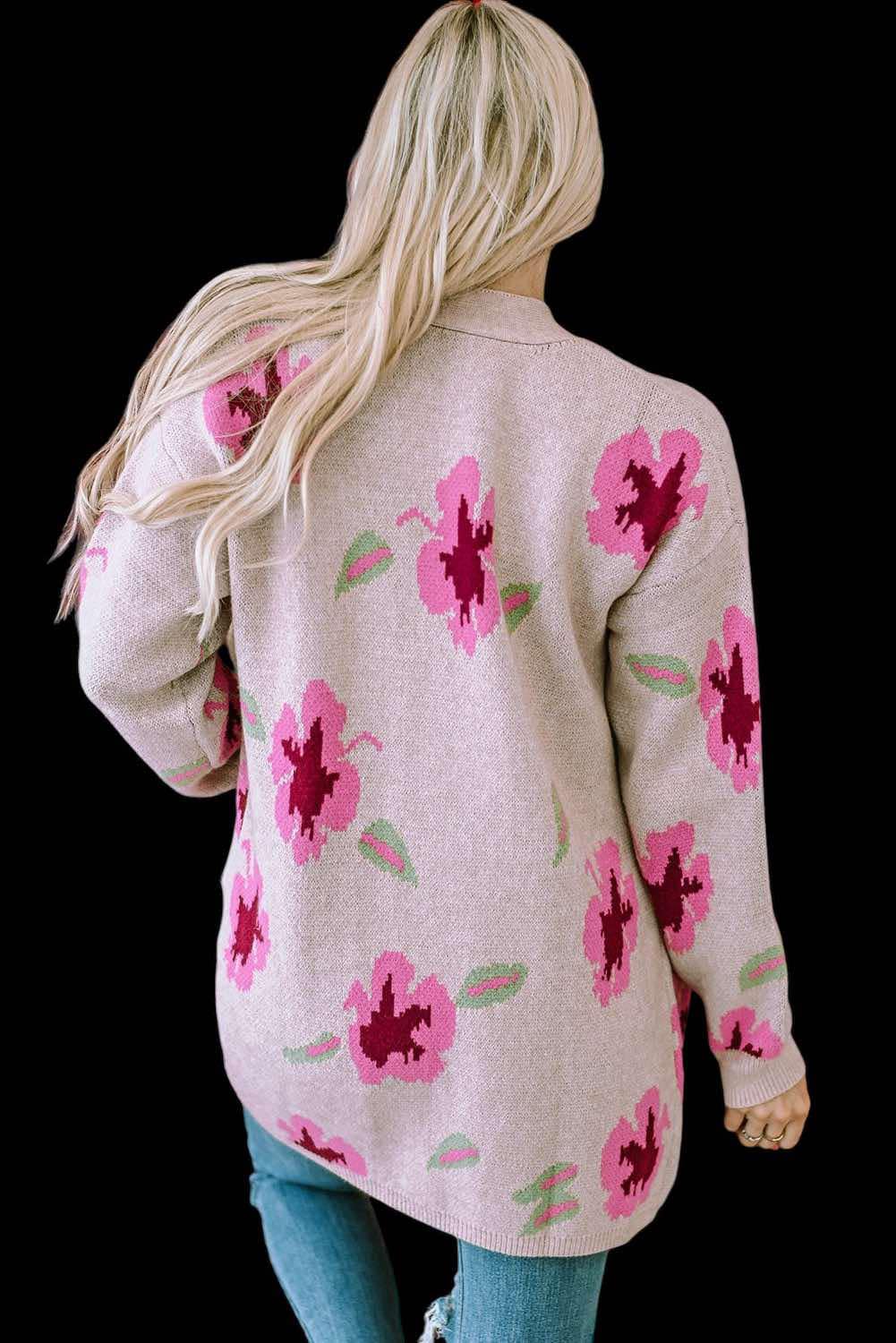 Woman wearing Cardi Girl floral cardigan with drop shoulders and pockets, featuring pink flowers on a beige background.