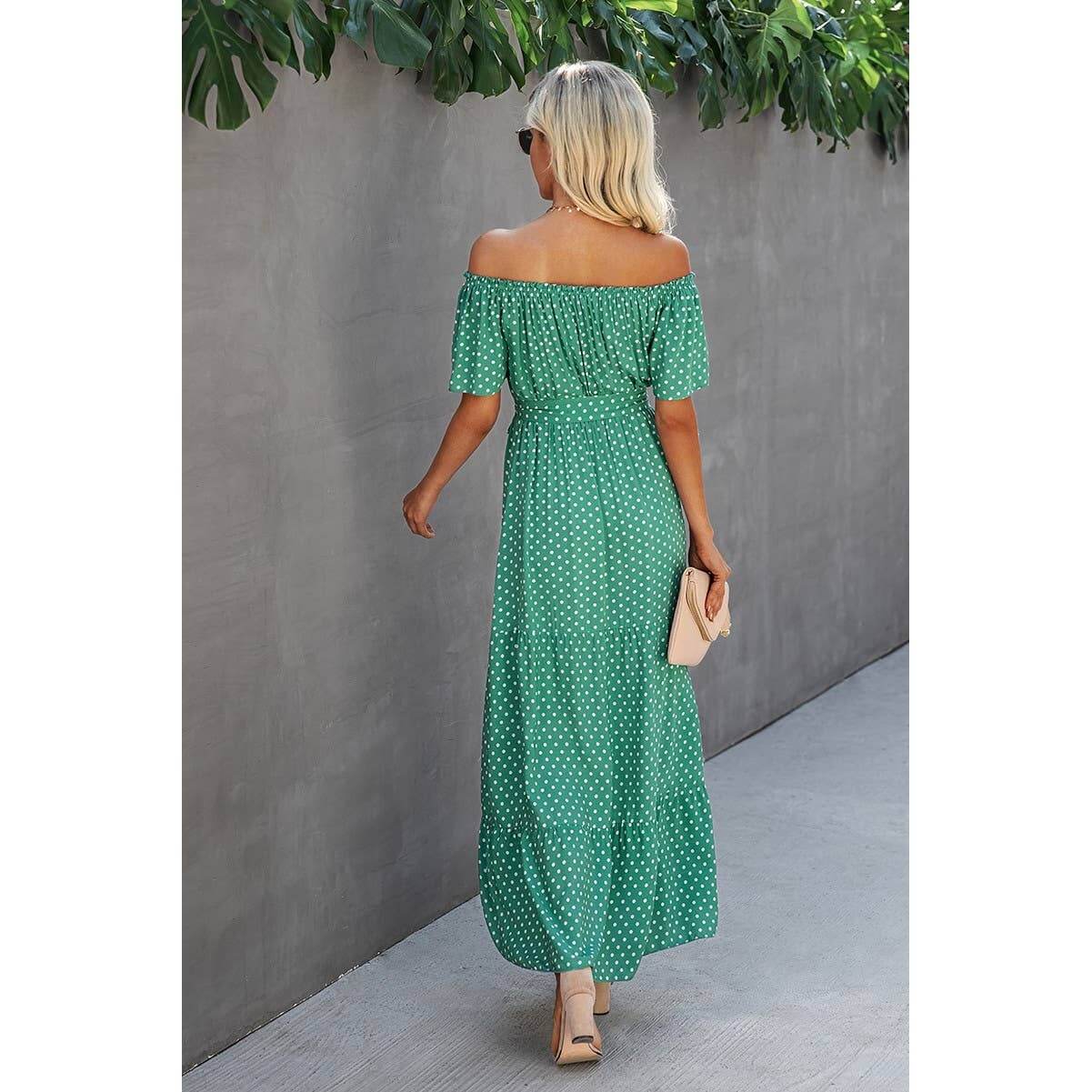 Woman in off shoulder green polka dot maxi dress with ruffled hem, perfect for casual outings or vacations.