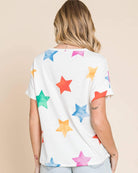 Model wearing a colorful star print t-shirt, featuring short sleeves and a casual style, paired with denim shorts.