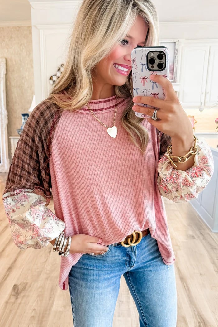 Woman wearing Mixed Blessings Top with patchwork bubble sleeves and ribbed fabric, holding a phone, showcasing casual chic style.