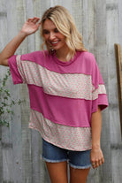 Woman wearing a fuchsia floral color block wavy rib pullover with shorts in a relaxed outdoor setting.