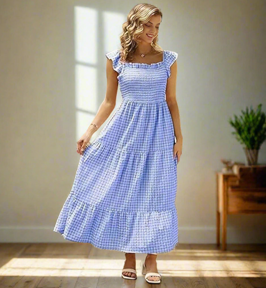 Woman wearing blue gingham smocked sundress with flutter sleeves and tiered skirt, exuding countryside charm.