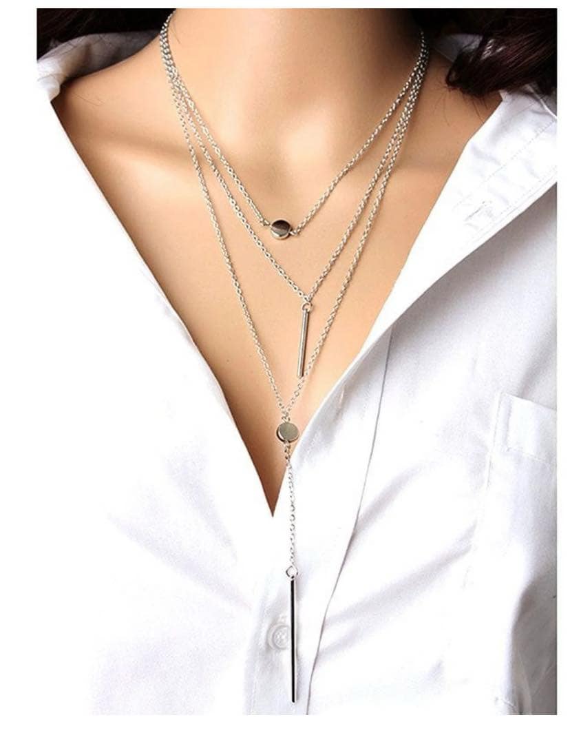Path Taken Necklace Set featuring layered silver chains with minimalist bars and polished discs, worn over a white shirt.