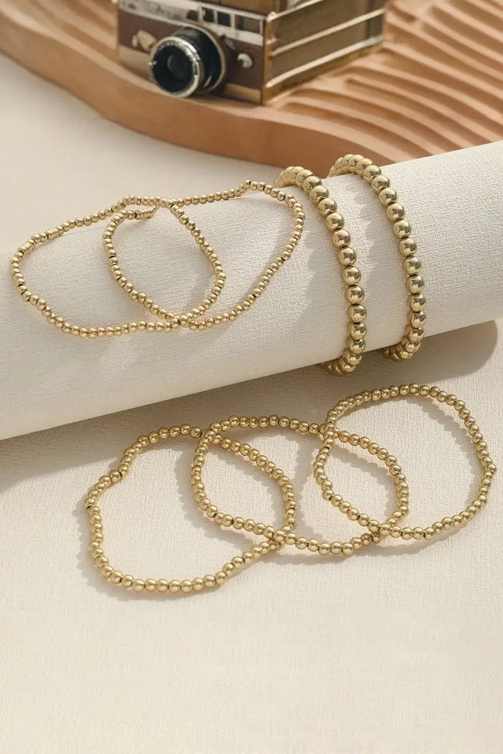 7-piece gold tone minimalist beaded bracelet set displayed elegantly on a soft surface.