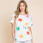 Model wearing a soft knit T-shirt with colorful star print, paired with denim shorts, showcasing a casual summer style.