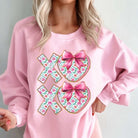 LOVE YOU MORE CREWNECK featuring XOXO floral print bows on cozy pink fabric, perfect for Valentine’s Day.