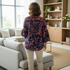 Woman wearing TIMELESS CHARM - Umgee (blue) top with floral pattern, seen from the back in a modern living room.