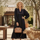 Model wearing GRACEFUL INSTINCTS MAXI DRESS with smocked detail and leopard trim, holding a bag near a dog.