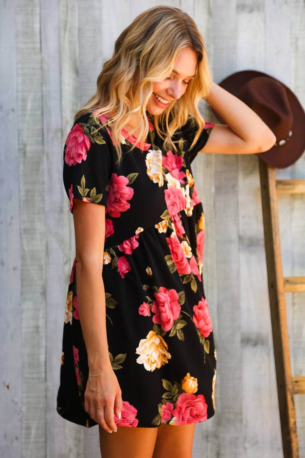 Floral mini dress with black backdrop, featuring vibrant pink and yellow blooms—ideal for garden parties.