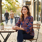 TIMELESS CHARM - Umgee (blue) top worn by a woman sitting at a café, featuring a floral design and 3/4 sleeves.