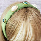 Heart pearl embellished headband displayed on a mannequin with blonde hair, featuring colorful embellishments on a green band.