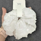 White pompom-textured Cloud Comfort scrunchie shown in hand, perfect for stylish hairstyles and accessories.