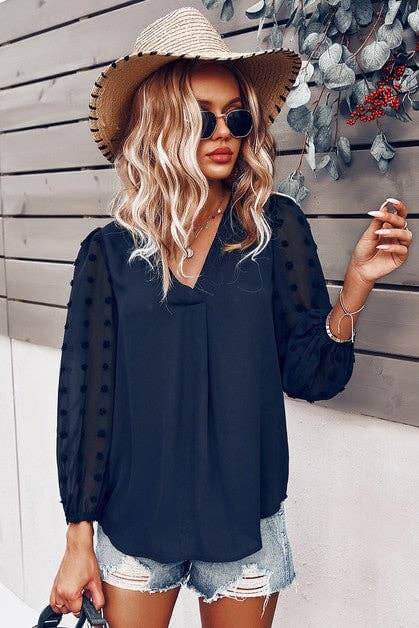 Chateau Charm Top in navy with flowy lantern sleeves, V-neckline, paired with stylish shorts and a wide-brimmed hat.