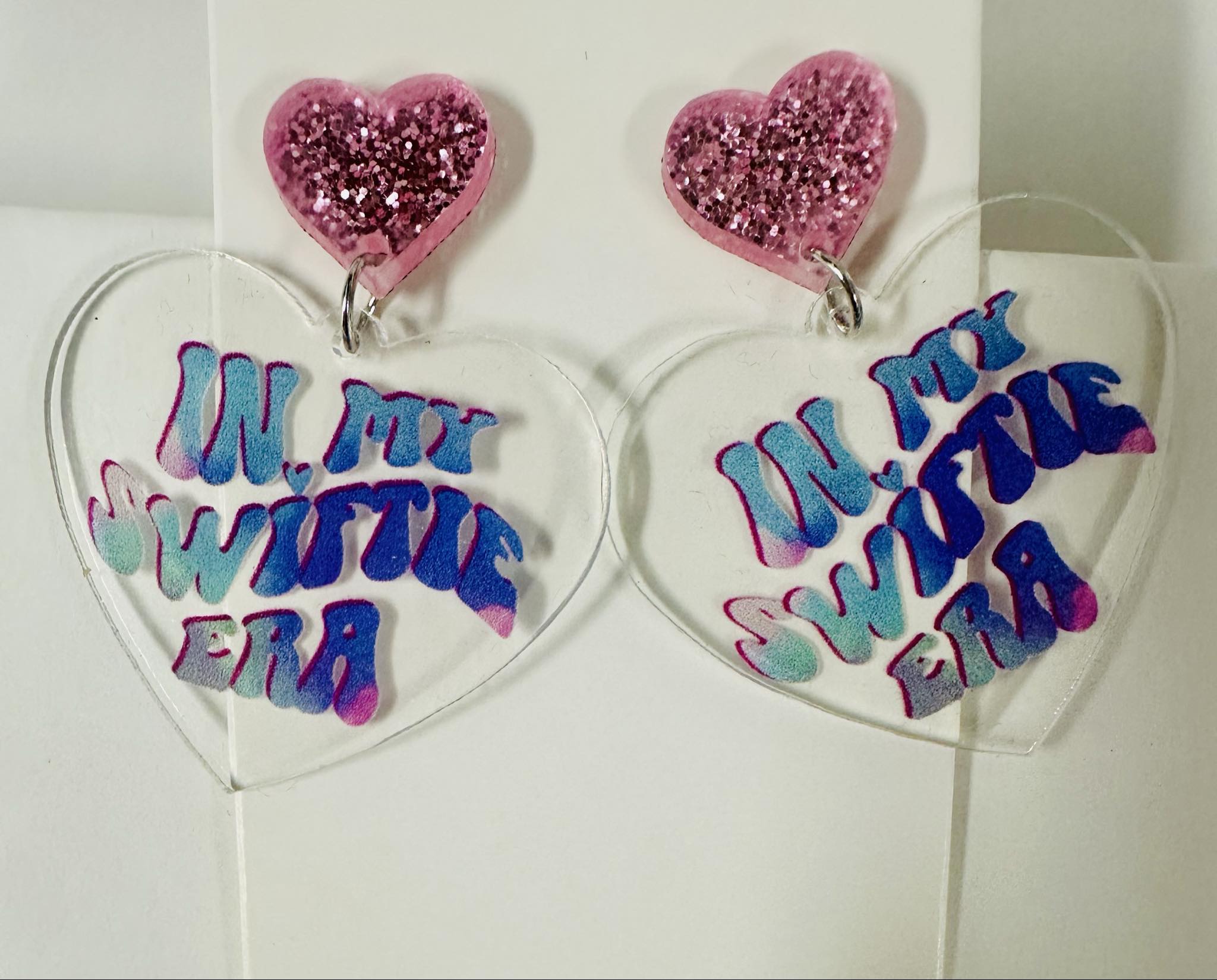 Clear acrylic heart earrings with 'In My Swiftie Era' text and pink glittery hearts, perfect for stylish statement accessories.
