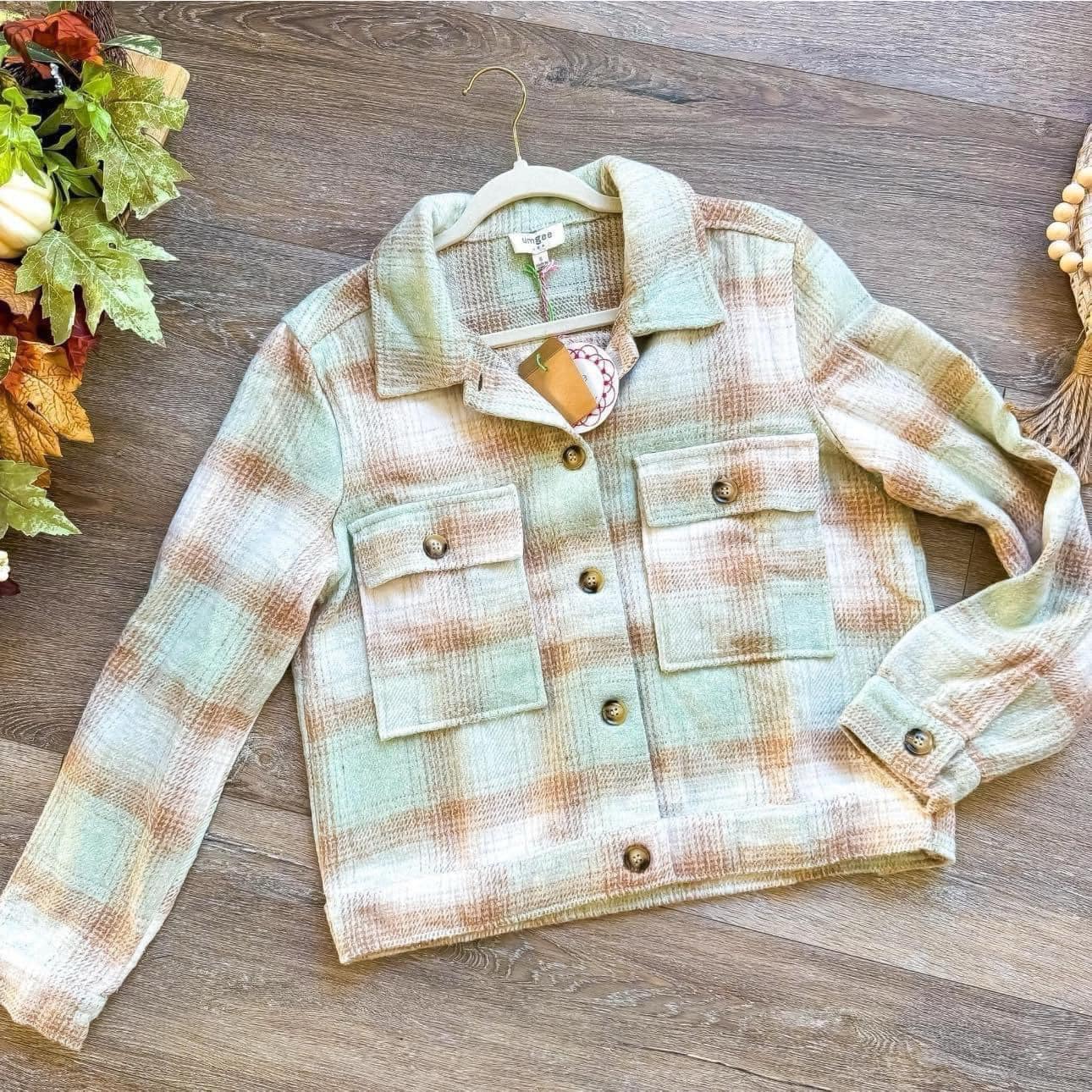 WARM EMBRACE plaid jacket by Umgee in pistachio and tan with tortoise shell buttons showcased on wooden floor.