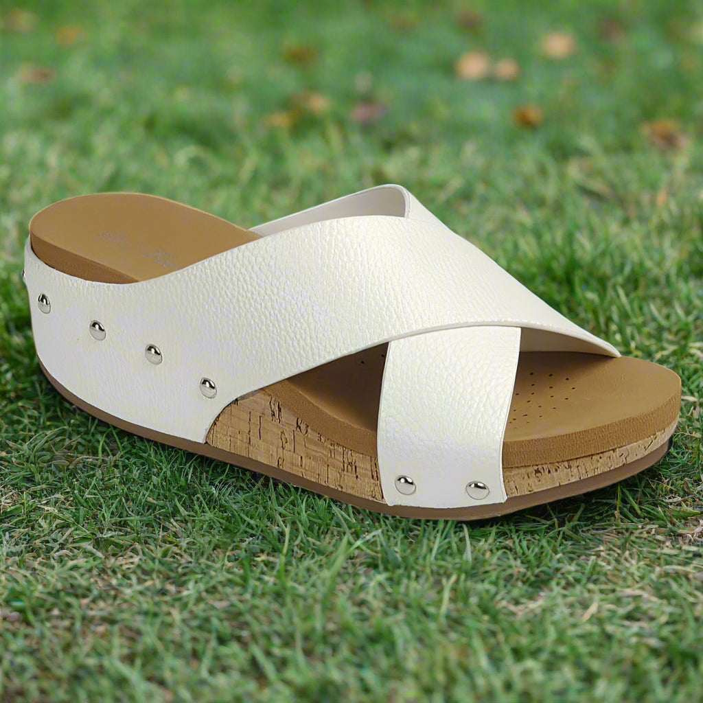Comfortable white cross-strap sandal with cork sole and decorative studs for casual summer style.