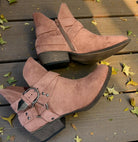VERY G CAROLINA ANKLE BOOT in rose tan suede with side zipper and buckle detail on wooden surface with autumn leaves.