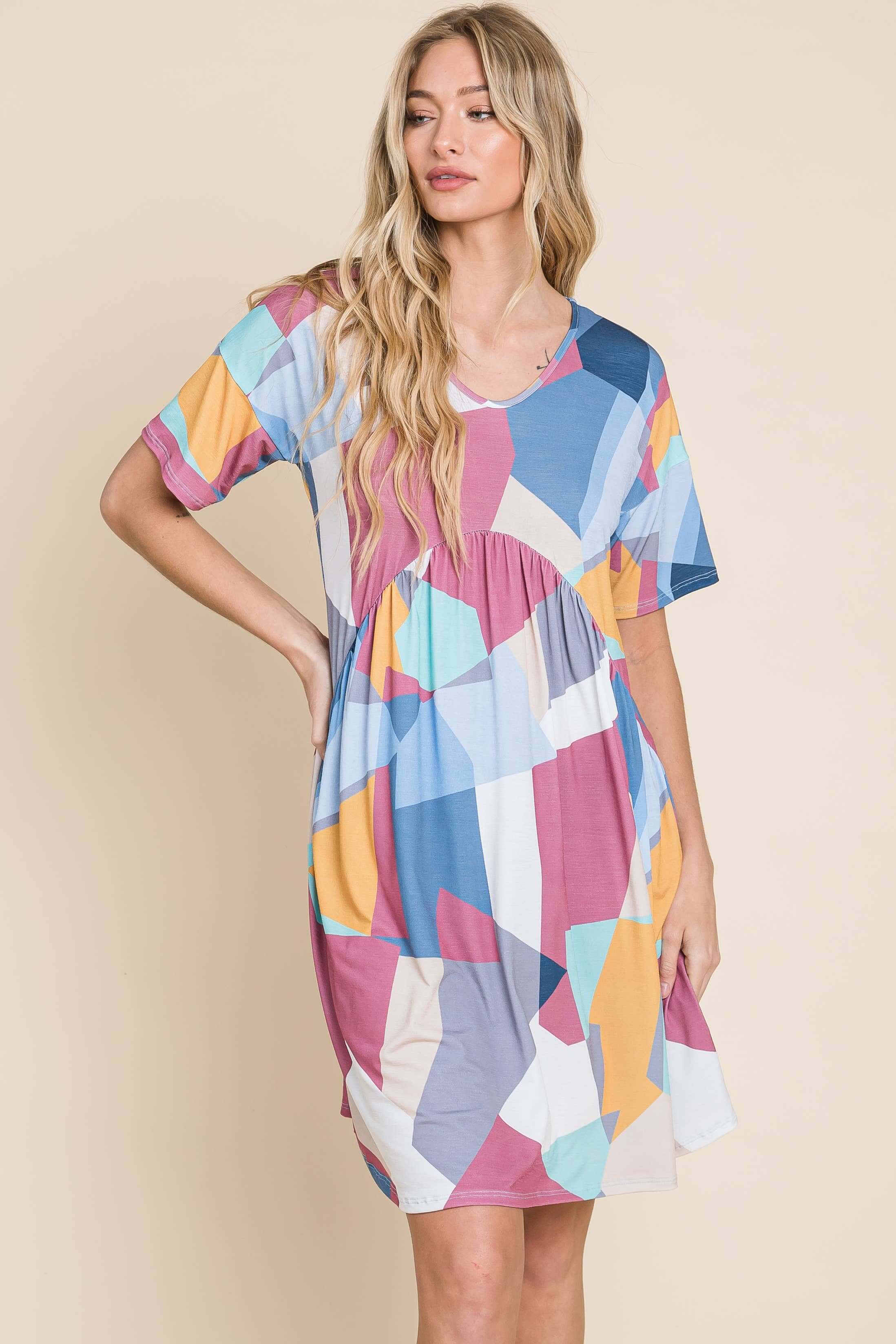 Model wearing DA1519 Shirred Waist Dress with multicolored geometric patterns and pleated babydoll style.