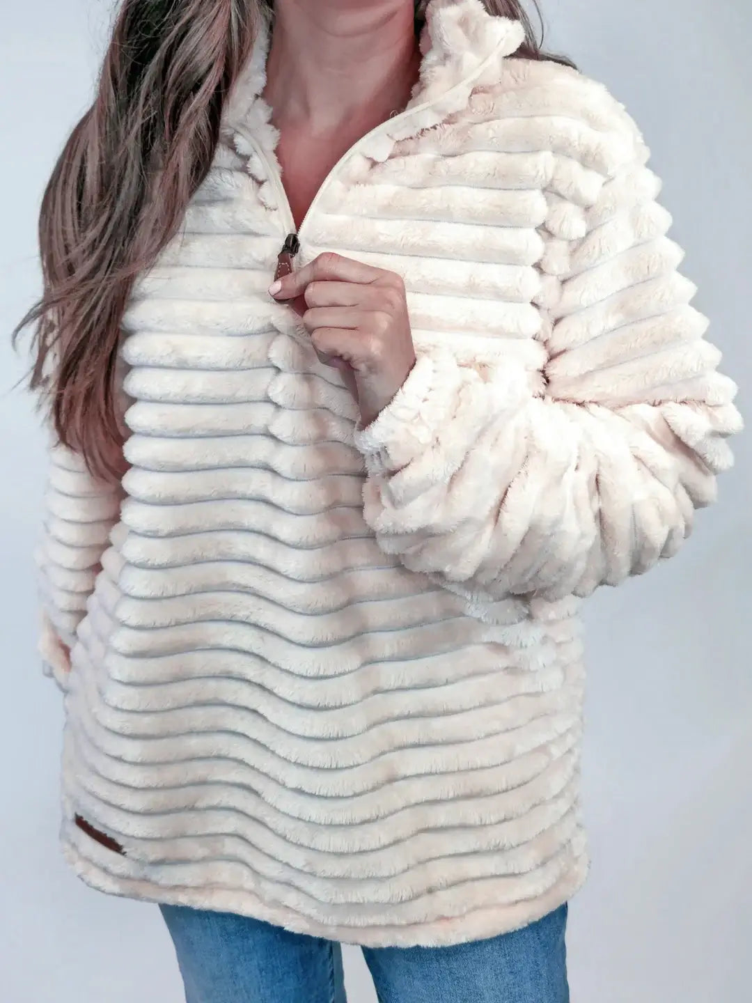 Woman wearing Simply Luxe Pullover in ivory snow, featuring ultra-soft material, quarter zip, long sleeves, and PU leather logo.