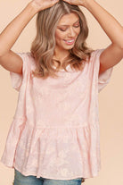 Woman wearing a pink embroidered floral top with a flowy babydoll silhouette, exuding elegance and comfort.