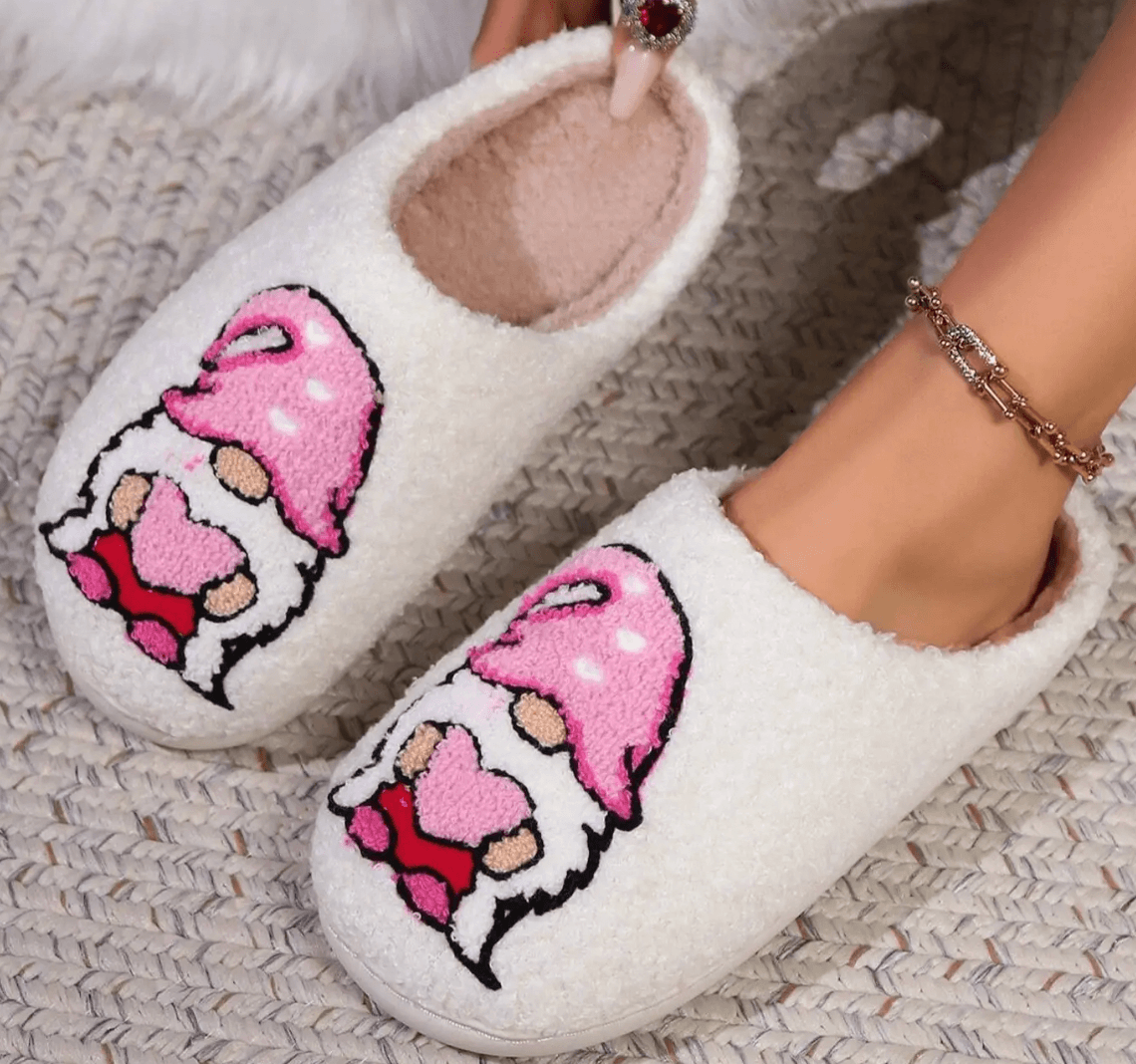 HUGS & HEARTS SLIPPERS featuring fluffy white sherpa and adorable embroidered character with pink hat and heart details.