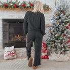 Model in FELINE FAB PANTS SET, showcasing cozy twisted rib texture and leopard patchwork detail by a festive fireplace.
