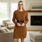 Model wearing a FIRESIDE STORY Sweater Dress in chestnut brown with a black belt in a cozy living room.