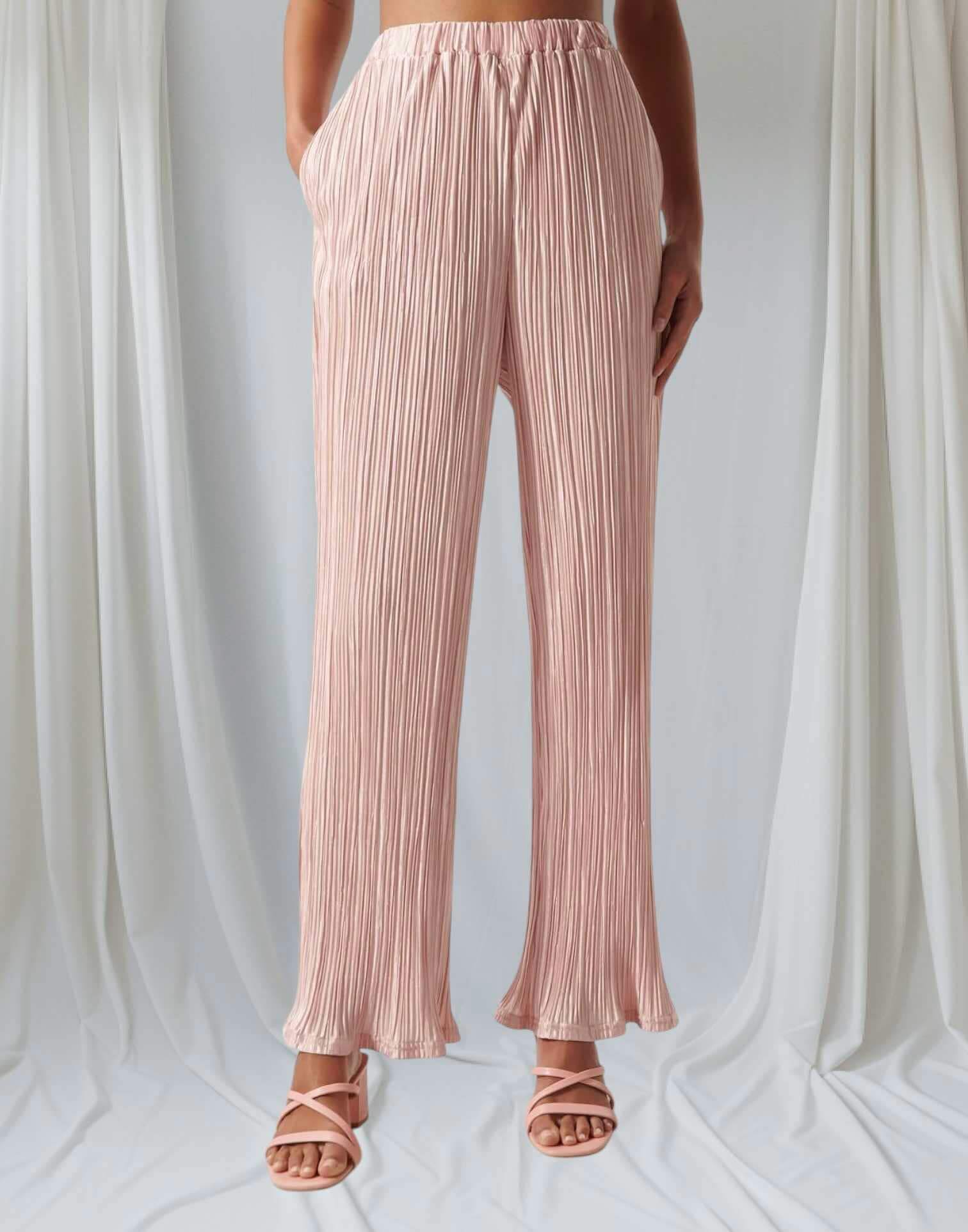 Blush pink plisse pants with a high waist and frill bottom, perfect for stylish daytime or evening wear.