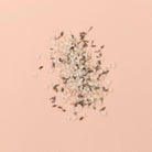 Petal-Infused Effervescent Mineral Bath Salts (Duo Pack) with lavender petals on a pink background.