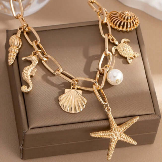 Gold charm necklace with starfish, turtle, seahorse, and shells from the Star of the Sea collection.