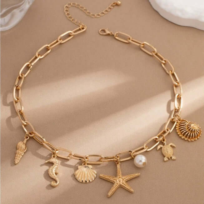 Gold tone charm necklace with starfish, turtle, seashell, seahorse, and pearl bead, inspired by the ocean.