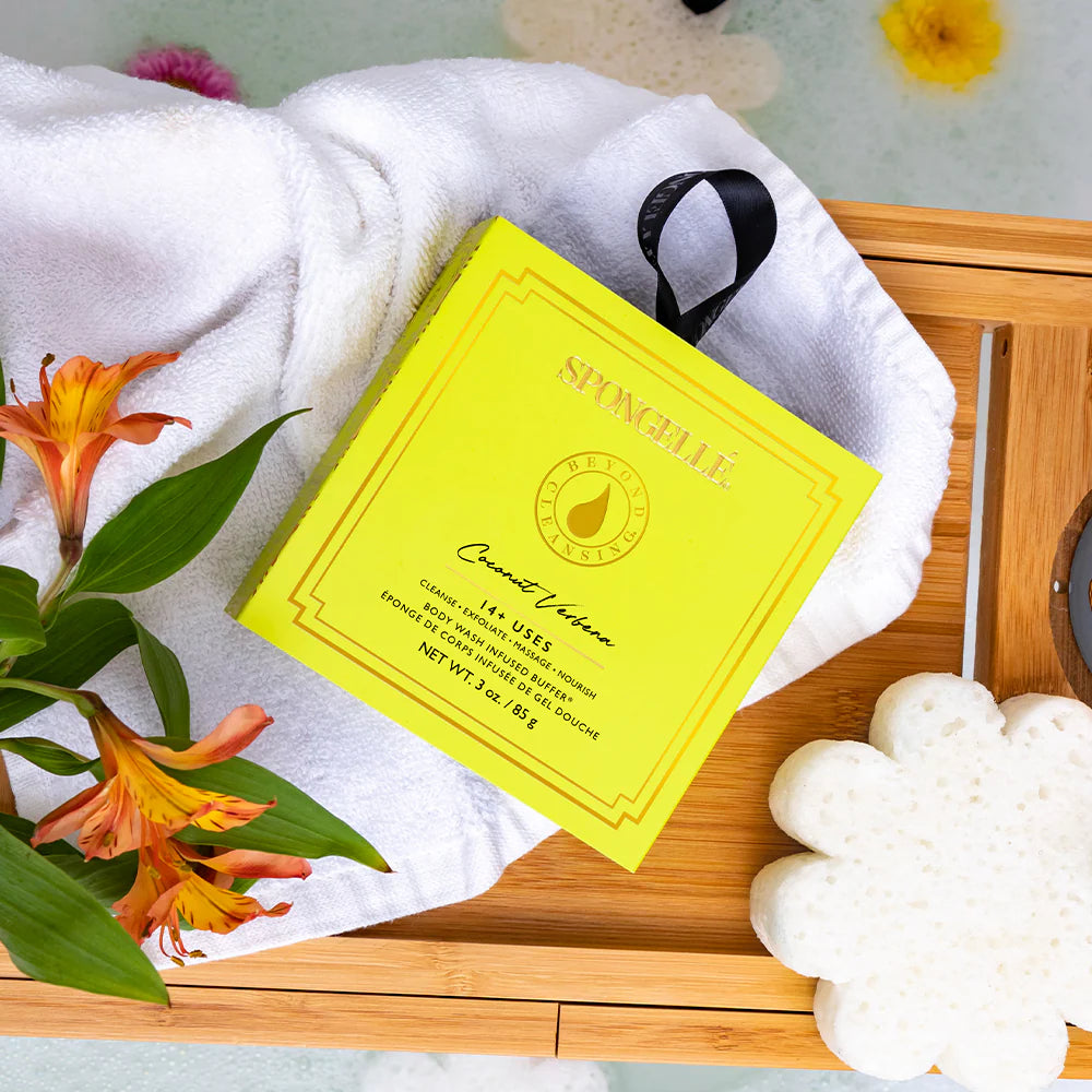 BEYOND CLEANSING COCONUT VERBENA by Spongelle in a vibrant yellow box on a wooden spa tray with flowers.