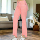 Sierra Sky denim jeans in flamingo pink, featuring a mid-rise fit and frayed hems, styled with white sneakers.