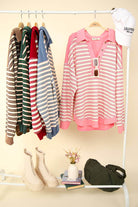 Oversized casual striped knit tops in various colors displayed on a rack, showcasing early fall fashion styles and accessories.