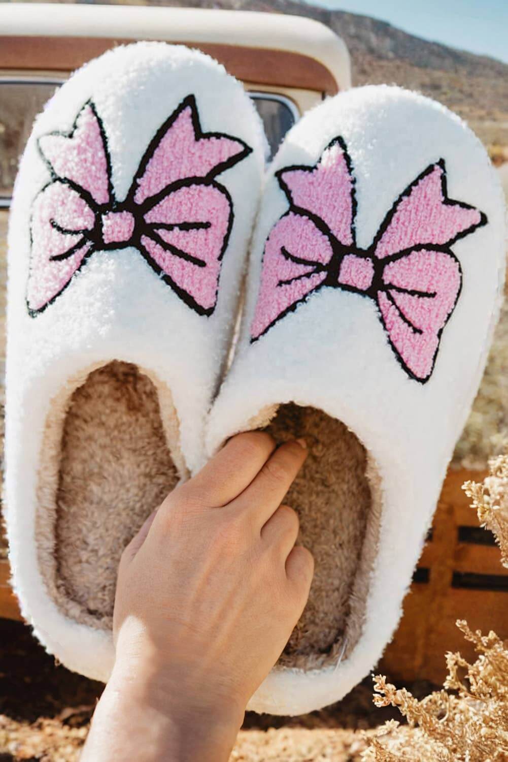 Cozy white slippers with pink bowknots, perfect for stylish indoor lounging and relaxation.