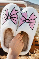 Cozy white slippers with pink bowknots, perfect for stylish indoor lounging and relaxation.