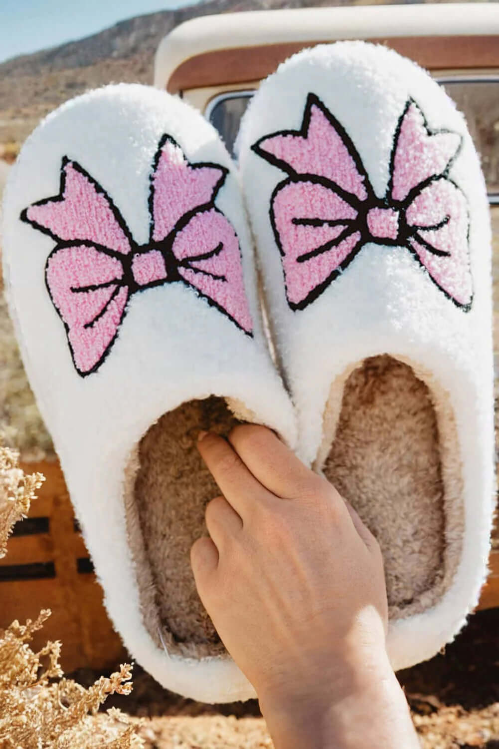 Cozy white slippers with pink bowknots, perfect for stylish comfort at home. Ideal for loungewear in chilly weather.