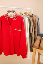 Oversized red contrast hoodie with button down and pocket, displayed with other cozy knit tops.