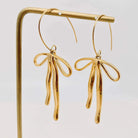 REFIEND RIBBON EARRINGS (2 colors) displayed in a polished gold finish, featuring a bow-inspired design.