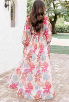 Back view of a model in a vibrant floral TROPICAL SENSATION DRESS, showcasing its elegant flow and design.