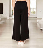 Back view of black ribbed wide leg pants from Sugarlips, featuring an elastic waist in a stylish interior setting.