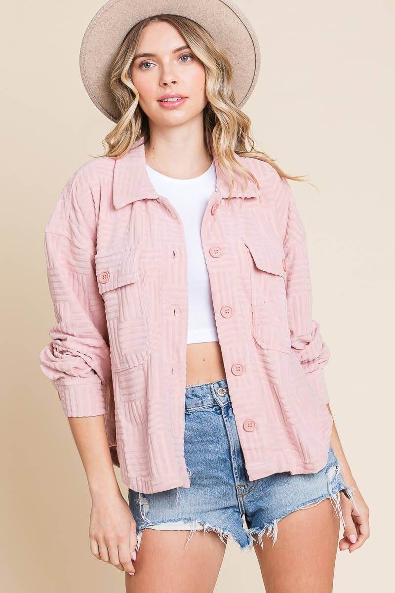 Women's soft pink embossed shacket with button-down front, styled with shorts and a hat for casual fashion.