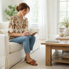 Woman wearing SOFT STRUCTURE TOP - She + Sky, enjoying her time reading on a cozy couch.