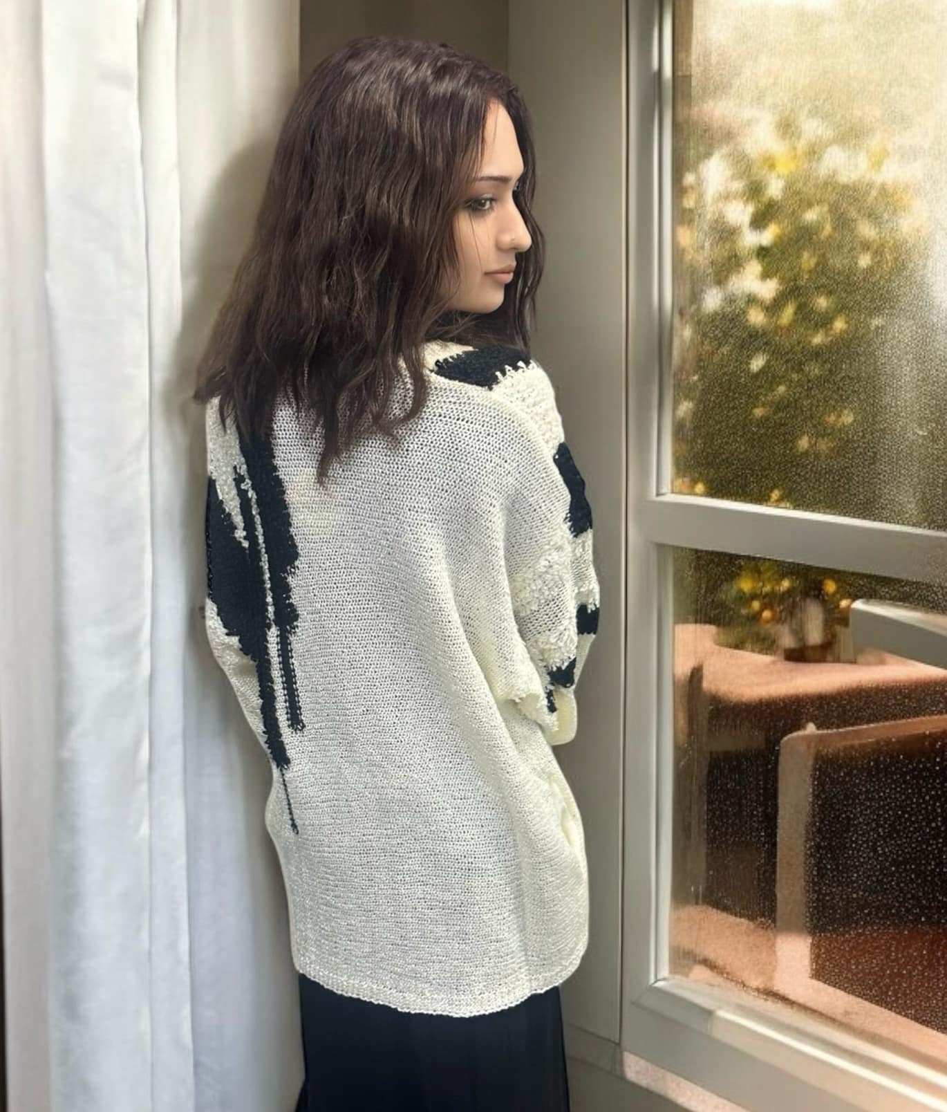 Woman wearing an ivory and black Ultra Soft Cardigan by KyeMi, featuring a fuzzy texture and casual style, standing by a window.